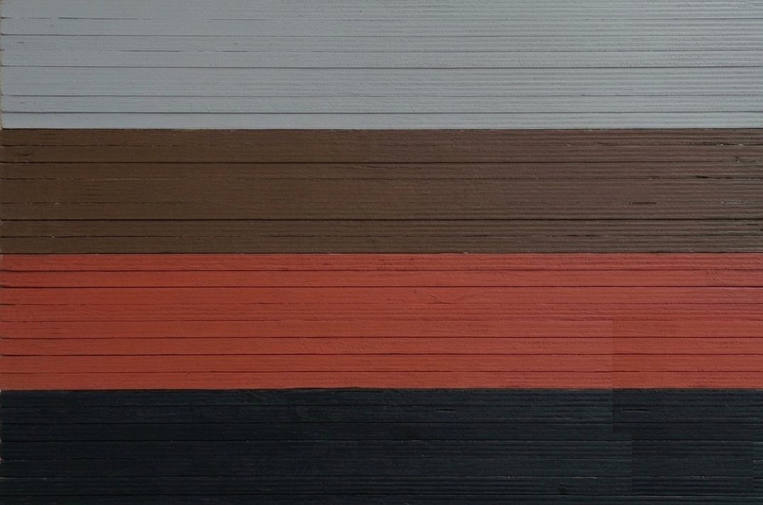 Pile de panneaux vue de tranche, chants peints en quatre bandes : gris, marron, rouge, noir