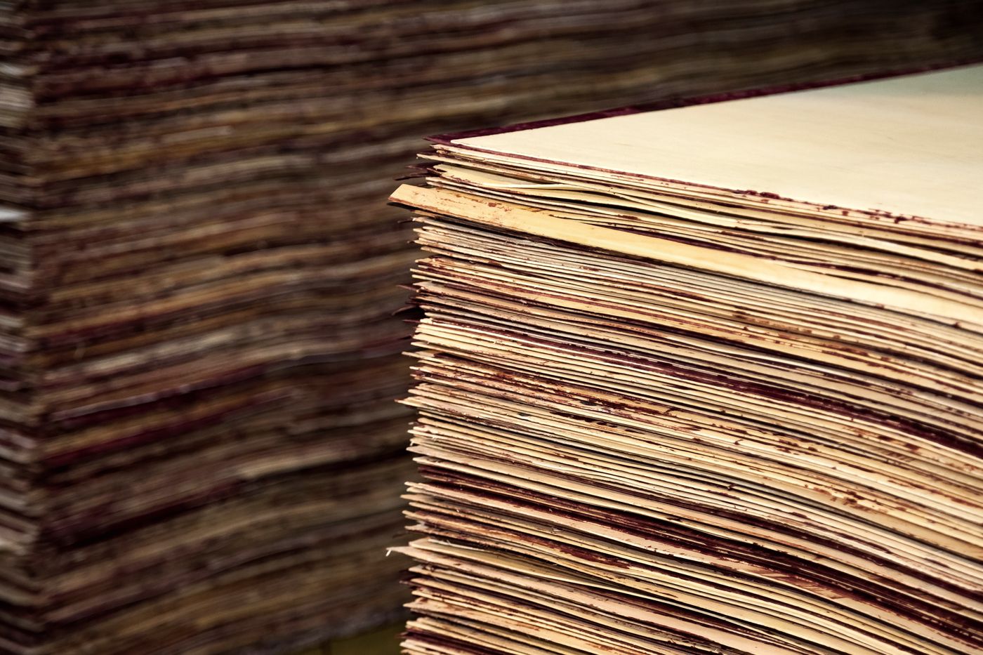 Pile de placages encollés en usine, lignes de colle visibles sur les chants